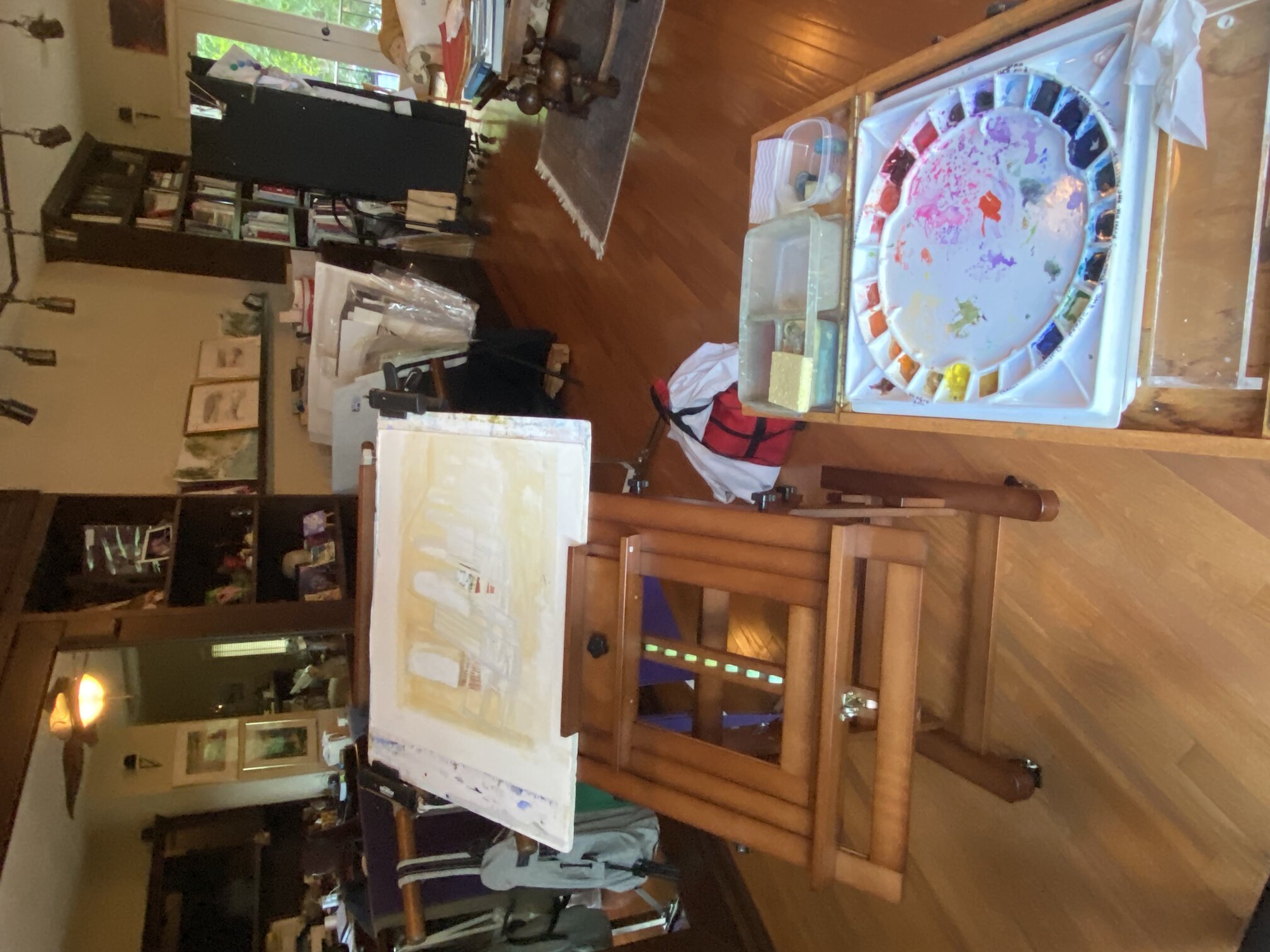 Artist studio with watercolor palette, easel, and painting in progress
